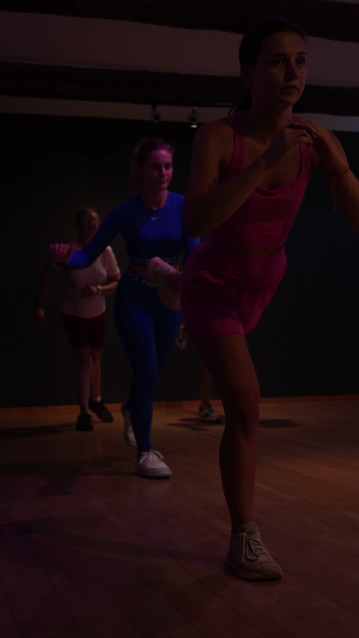 Un cours de cardio dance en pleine action dans la salle du studio.