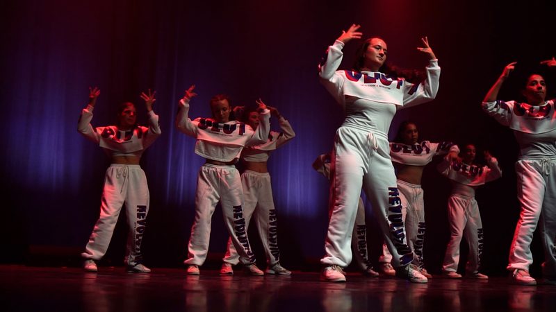 Le groupe en survêtements blancs, en position, sous une lumière rouge.