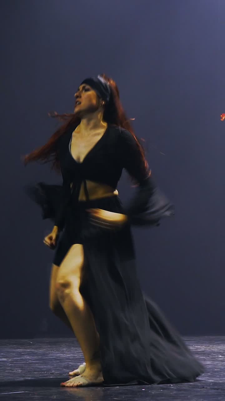 Méli seule sur le plateau, en robe noire, les cheveux en mouvement, dans une seule douche de lumière blanche.
