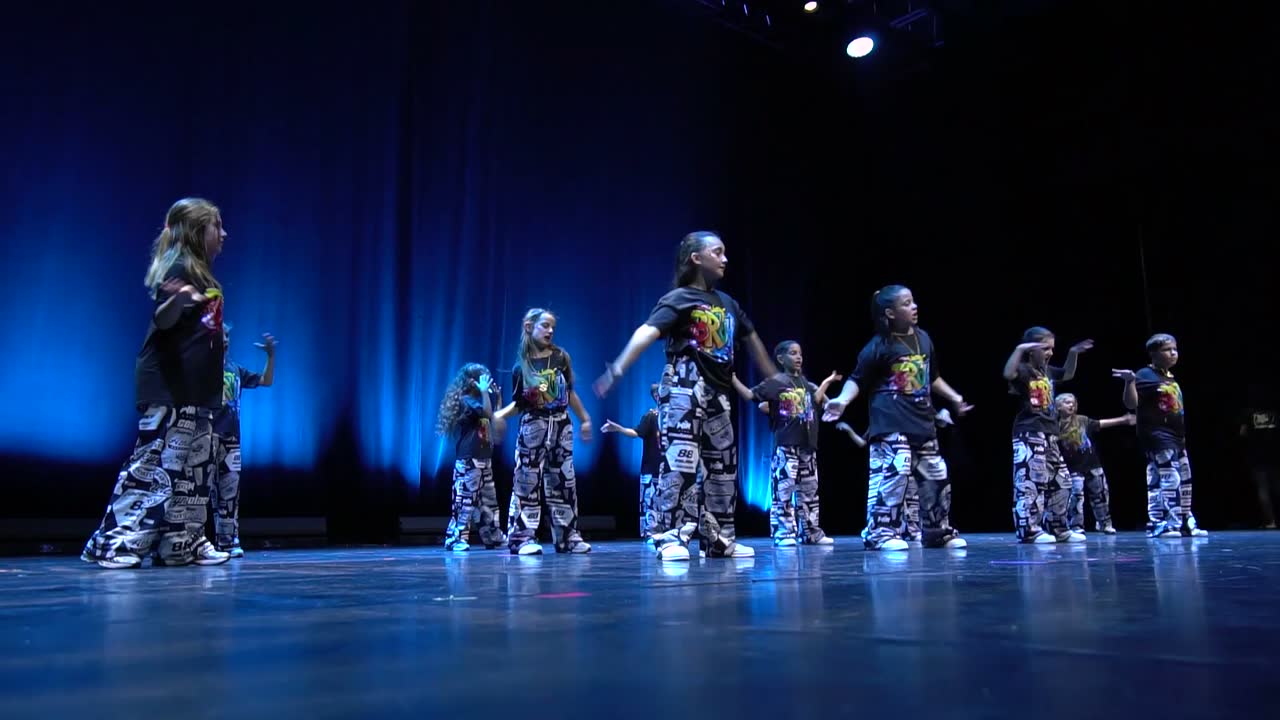 Le groupe des 6-8 ans en tenues imprimées bleu et noir, sur une scène baignée de bleu.