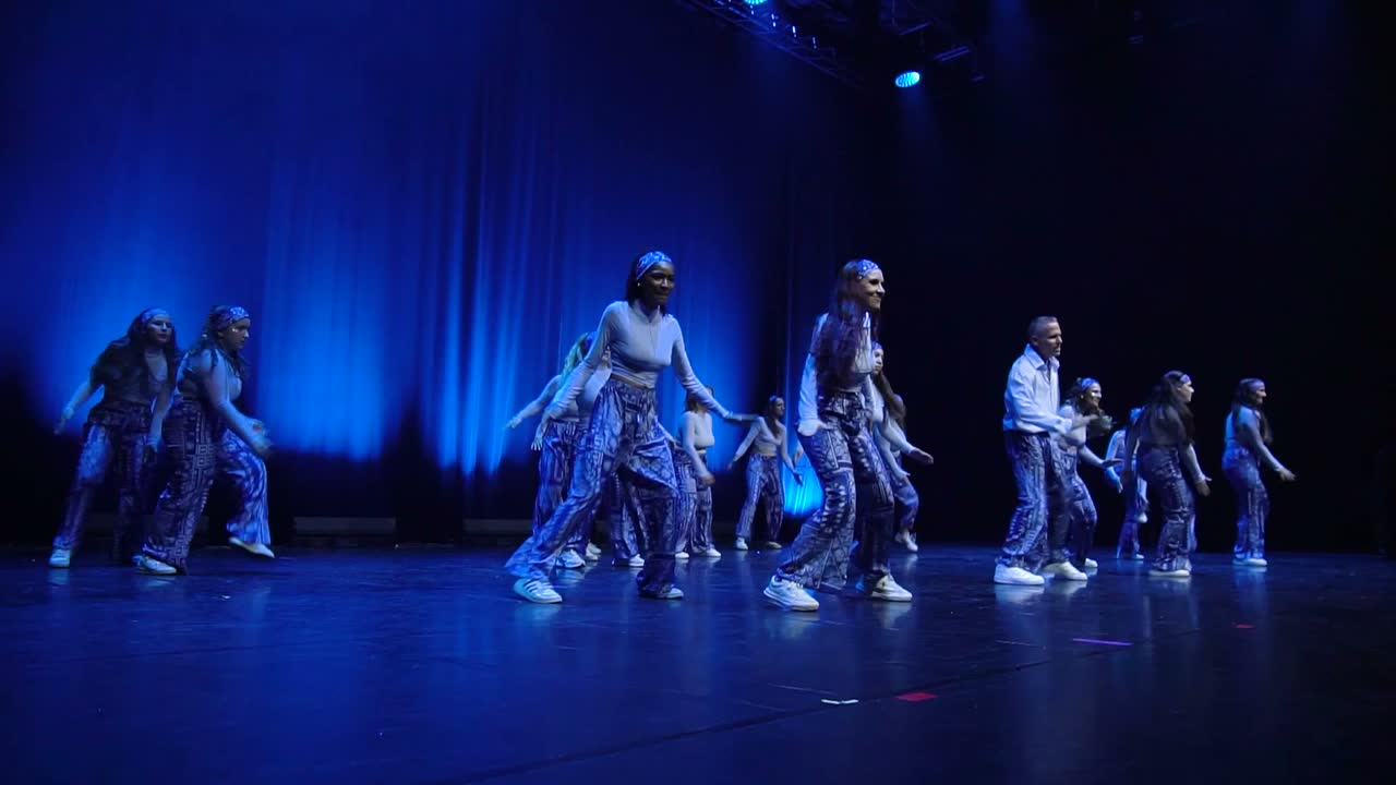 Le groupe hip-hop niveau 1 en jeans et tee-shirts, sur une scène bleue.