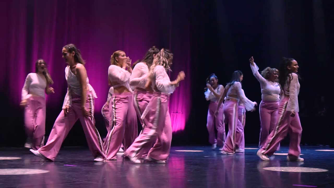 Le groupe lady niveau 2 en ensembles satinés roses, en ligne devant un fond magenta.