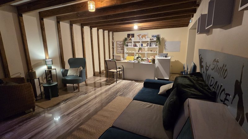 L'espace d'accueil du nouveau local : canapés, fauteuils, bureau et le logo Studio M DANCE peint au mur.